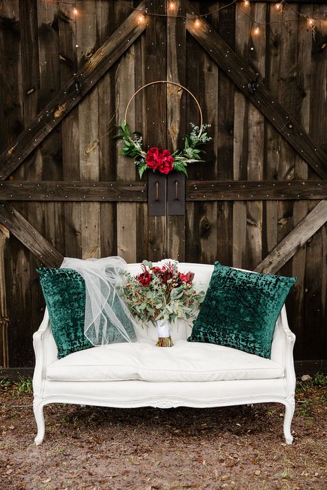 Rustic Christmas Inspired Wedding Decor, Wooden Barn Backdrop with White Vintage Loveseat with Green Pillows and Wedding Veil, Wedding Bouquet with Red Florals and Greenery, Hanging Gold Floral Hoop with Red Roses | Bushnell Florida Christmas Inspired Wedding, Red And Pink Wedding, Vintage Loveseat, Barn Backdrop, Christmas Wedding Themes, Christmas Wedding Decorations, Wooden Barn, Christmas Mini Sessions, Wedding Winter