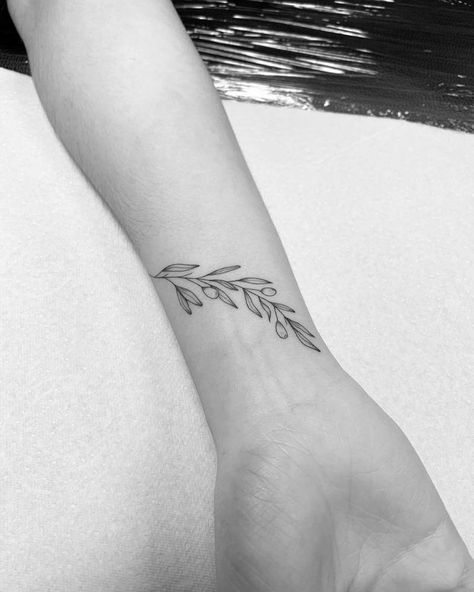 Athena Olive Branch Tattoo, Wrist Olive Branch Tattoo, Greek Wrist Tattoos, Olive Branch Line Art Tattoo, Olive Wrist Tattoo, Olive Vines Tattoo, Olive Branch Tattoo On Wrist, Olive Branch Band Tattoo, Delicate Olive Branch Tattoo