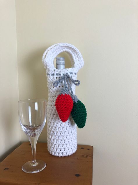 Hand crocheted, Christmas present embellished wine or bottle gift bag  - perfect for hostess gifts, holiday parties,  appreciation gifts.  Any standard 750 ml wine/liquor bottle will fit.  Also great for carrying water bottles. Note that the bulb colors on each may vary from the photographs.  Please note in the comments if you would like specific bulb colors. This bag features a different color backgrounds tied with a sparkly cord attached to two three-dimensional Christmas tree lights!  These r Crochet Wine Bottle Cover Free Pattern Christmas, Fall Crochet Patterns Free, Wine Cozy, Crochet Wine, Wine Sleeve, Christmas Wine Bottle Covers, Wine Bottle Sleeves, Bottle Caddy, Crocheted Christmas