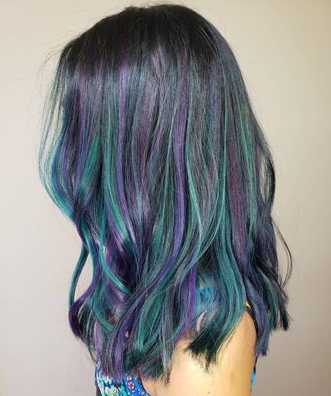 How can you say no to this trend? It's a fusion of purple and emerald green highlights on dark hair that creates a stunning dimension. Purple And Teal Highlights, Purple To Green Ombre Hair, Purple And Green Hair Streaks, Blue And Green Highlights In Brown Hair, Blue Purple Brown Hair, Geode Hair Color, Black Green Purple Hair, Blue Green Hair Color Ideas, Purple Hair With Green Highlights