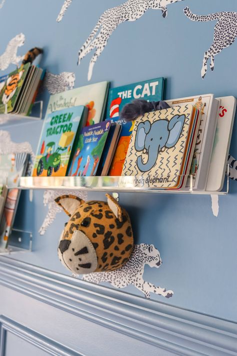 closeup of acrylic shelves with books in adventure themed nursery with leopard wallpaper Colorful Boy Nursery, Eclectic Baby Nursery, Blue Baby Nursery, Shelves With Books, Adventure Themed Nursery, Toddlers Bedroom, Baby Blue Nursery, Kids Bedroom Wallpaper, Acrylic Shelves