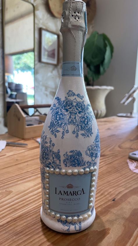 Each bottle is meticulously adorned with a vintage blue floral pattern, creating a unique piece that can serve as a stunning centerpiece, a decorative accent, or a thoughtful gift. It is perfect for bridal showers, bridesmaids gifts, bachelorette parties, weddings, graduations, and housewarming gifts!  I source floral prints that match the color and design of the bottle and hand paint and decoupage each one, so each bottle is unique. To top it off, each bottle comes wrapped with a beautiful bow. Here are a couple notes about the product before you order:  > There are two sizes, one 750mL and the other mini version of 187mL - the mini's are great as party favors! Discounts for orders of more than one mini bottle are incorporated in the pricing.  Bride Gift, Bridal shower gift, Bridesmaid gi Bridal Shower Gifts For The Bride, Creative Bridal Shower Gifts For Bride, Decorating Liquor Bottles, Bride Champagne Bottle, Champagne Gift Ideas, Bridal Shower Winery, Belle Party Favors, Couple Notes, Fancy Wine Glasses