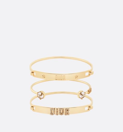 This season's Dio(r)evolution bracelet set is offered with a new finish. The three gold-finish metal bangle bracelets are enhanced by the 'DIOR' signature and amber-colored crystals. The modern and elegant bracelet set may be coordinated with other creations from the Dio(r)evolution line. Bracelet Dior, Dior Bracelet, Gold Bracelet Set, Christian Dior Couture, Dior Couture, Elegant Bracelet, Hook Clasp, Amber Color, Boutique Online