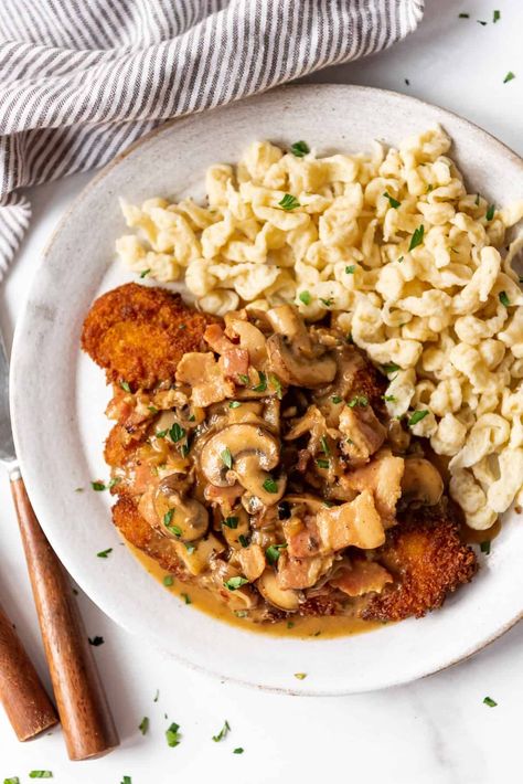 Pork Schnitzel with bacon mushroom gravy is an easy 30-minute weeknight dinner that is a family favorite! The pan-fried pork chops are crisp and golden on the outside, but tender enough to cut with a fork. This easy German jägerschnitzel recipe is perfect with mashed potatoes, egg noodles, späetzle, or rice and a veggie on the side. | jagerschnitzel recipe authentic | german pork schnitzel mushroom gravy | pork schnitzel with mushroom gravy | pork schnitzel recipe germany mushroom gravy Schnitzel And Spaetzle, Jagerschnitzel Recipe, Gravey Recipe, Pork Snitzel, Jaegerschnitzel Recipe, Pork Schnitzel Recipe, Schnitzel Recipe, Pork Mushroom, German Food Authentic