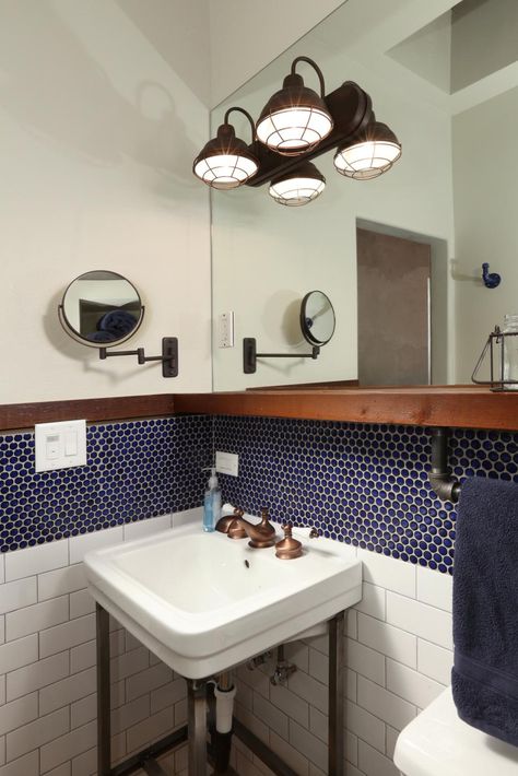 Reclaimed wood shelves add function to this custom bathroom renovation. In the space, contemporary blue penny tile mixes with traditional white subway tile for a layered, transitional feel. The space features antique bronze accents. Room Tiles Wall, Blue Penny Tile, Unique Bathroom Tiles, Industrial Bathroom Design, Bathroom Wall Hanging, Bronze Fixtures, Reclaimed Wood Shelves, Penny Tile, Vintage Industrial Decor