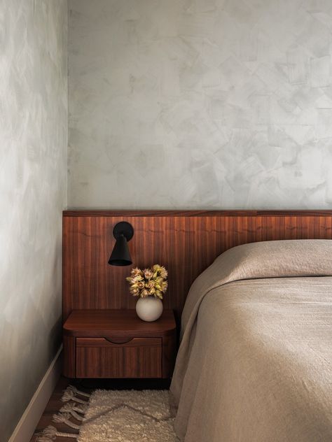 The interiors of this Brooklyn condo feature neutral tones, wholesome natural materials and fibers, and subtle textures. Many of the walls are brush painted with Lime Wash, to give them a subtle textural interest. The primary suite features a custom walnut built-in headboard and side tables, a bookshelf and dresser, custom wardrobe millwork, and a sliding door with slatted detailing. Built In Bed Side Tables, Built In Bed Headboard, Built In Headboard Wall, Wall To Wall Headboard, Headboard With Side Tables, Built In Headboard, Tv In Bedroom Ideas, Shapeless Studio, Low Ceiling Bedroom