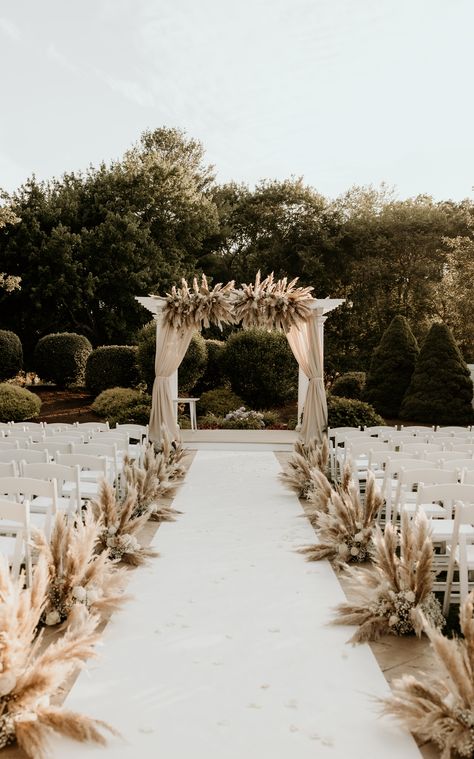 We're obsessed with this pampas grass wedding decor featuring arch draping, an aisle runner, and aisle decor. | Photography: Cami P Photography Pampas Grass Wedding Ceremony Aisle, Pampas Chair Decoration, Pampas Grass Wedding Aisle Decor, Pampas Grass Wedding Decor Isle, Pampas Down The Aisle, Wedding Arch Ideas Pampas, Wedding Ceremony Runner, Flowers Down The Aisle Wedding Outside, Outdoor Wedding Aisle Ideas Boho