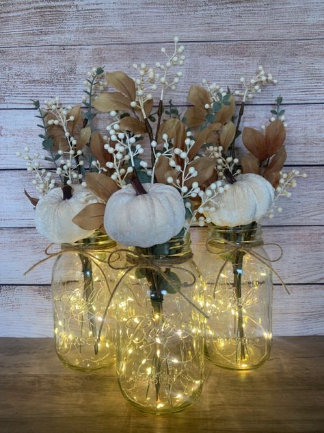 These charming Fall Mason Jar Centerpieces are a perfect addition to your seasonal decor! Also ideal for a fall wedding or fall bridal shower. Mason Jars are Ball Regular Mouth Quart Size jars. Each floral arrangement will include - a white velvet pumpkin pick, three eucalyptus stems and a brown paper stem with branches of cream colored berries and brown leaves. A piece on twine will be tied to the top of each jar. And a 7ft set of warm white fairy lights will be included for each jar if p Mason Jars With Candles, Fall Mason Jar With Fairy Lights, Fall Cocktail Table Centerpieces, Fall Wedding Centerpieces Diy Table Centers Simple Mason Jars, Pumpkin Table Centerpiece Wedding, Fall Theme Centerpieces, Fall Wedding Ideas Pumpkins, Fall Pumpkin Wedding Decor, Mason Jar Centerpieces Table Decorations