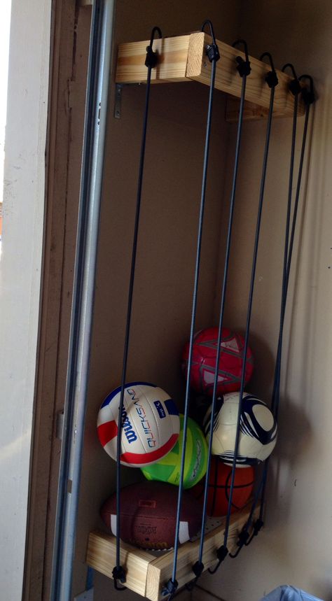 Ball storage for garage using bungee cords.  My husband finished it recently.  He said he wished he would have used thinner wood.  He stated it would have been easier to hook the bungee cords into it.  The wood he used ended up being too thick so he had to drill holes for the cords--- this works because the cords don't slide back and forth, but drilling into the wood was time consuming, he said. Thanks hon! Storage For Garage, Diy Storage Projects, Garage Organisation, Diy Toy Storage, Feather Wall Decor, Garage Storage Solutions, Garage Organization Diy, Garage Organize, Ball Storage