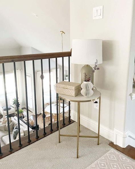 A neutral-colored staircase landing is decorated with a gold and marble-topped end table, a nesting box, a curved floral vase, and a taupe table lamp. The woven runner and tassel rug layer with the taupe decor perfectly...   Image: threetimesahome Decor Top Of Stairs, Small End Table Decor, Colored Staircase, Stairs Landing Decor, Staircase Landing Decor, Landing Decor Ideas, End Table Decor Ideas, Taupe Decor, Stair Landing Decor