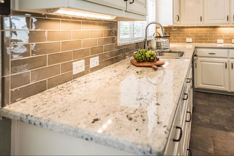 Light brown subway tiles with white grout in a modern kitchen. Colonial White countertops with under counter lighting and white cabinets. Dark brown-grey mixed contemporary porcelain tiles flooring. Beautiful light green wall paint and dark hardware. A subway tile backsplash always gives a timeless vibe to the kitchen. #colonialwhitegranite #colonialwhitegranitecountertops #lightbrownbacksplash #whitekitchencabinets #browngraymixedporcelainfloortiles #colonialwhitegranitekitchencountertops White Granite Kitchen Countertops, Colonial White Granite, Kitchen Countertop Colors, Light Colored Granite, White Granite Countertops Kitchen, Light Granite Countertops, Brown Granite Countertops, Granite Kitchen Countertops, White Granite Kitchen