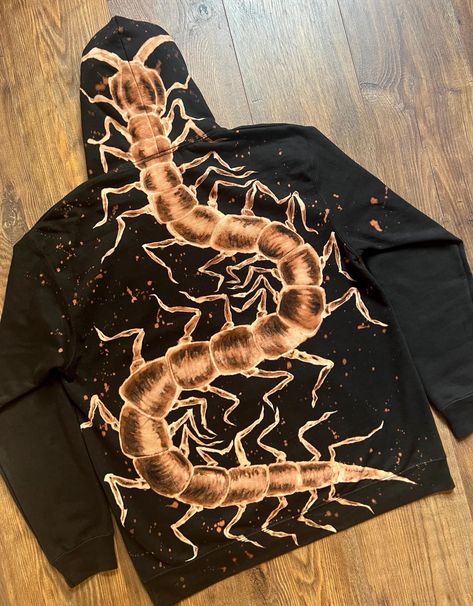 A one-of-a-kind hand painted sweatshirt featuring a unique centipede design by the artist Donnie at MadeByDustBunnies. Meticulously painted using bleach, the design will not fade or deteriorate over time. The centipede design is on the back of the jumper with decorative splatters. The splatters also feature all over the hood. If you would like a bleach painted jumper in a different design, please get in touch for custom orders. I can paint jumpers, hoodies, joggers and t-shirts in any size and l Brown Bleached Shirt, Bleach Art Hoodies, Painting On A T-shirt, Bleach Designs On Clothes, Painted Shirt Designs, Moth Bleach Design, Bleach Sweatshirt Designs, Bleach Jacket Design, Bleach Clothing Art