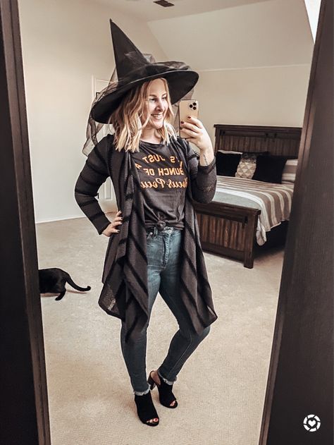 Easy last-minute witch costume idea using clothes from your closet! Pair any Halloween graphic tee with a black open front cardigan, frayed hem jeans and open-toe mule heels, then top with a witch hat for a chic, festive and fashionable costume! 🖤 | La Vida Lati Western Witch Costume, Modest Witch Costume, Good Witch Costume For Women, Witches Customes, Mom Witch Costume Diy, Cute Witch Costume For Women Diy, Work Appropriate Witch Costumes, Modern Witch Costume Diy, Easy Witch Outfit