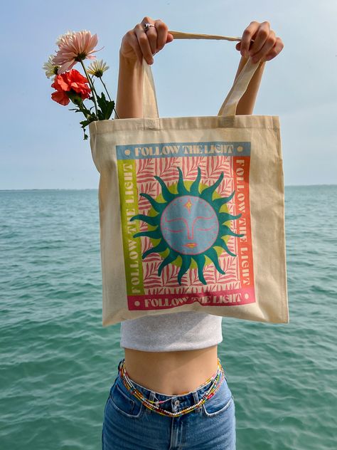 "Follow the light tote bag, perfect for the beach this summer! Designed by me :)  A 100% cotton tote bag is the champion of durability, sustainability, and style.  .: Material: 6 oz./yd², 100% natural cotton canvas fabric .: One size: 15\" x 16\" (38.1cm x 40.6cm) .: Convenient self-fabric handles .: Double-sided print" Painted Beach Bag, Denim Paint, Follow The Light, Book Illustration Design, Summer Tote Bag, Summer Beach Bag, Tote Bag Beach, Tote Bag Aesthetic, Summer Tote Bags