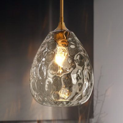 Contemporary minimalism meets glam sophistication in this single pendant. Crafted from metal, this pendant lighting features a bell-shaped lampshade capped with streamlined support, a molded sconce, and a slim, height-adjustable download. The clear hammered glass with elegant patterns dynamically interacts with the lighting from one type A max 60W bulb(not included), diffusing a warming ambiance and sparkling a unique visual delight that resembles the water ripple effect. Crisp and stylish, enha Over Tub Lighting Master Bath, Glass Globe Pendant Light Over Island, Hammered Glass Pendant Lighting, Textured Glass Pendant Light, Modern Pendant Lights Over Kitchen Island, Bathtub Pendant Light, Bathroom Pendant Lighting Vanities, Gold Kitchen Lights, Gold Island Pendant Lights