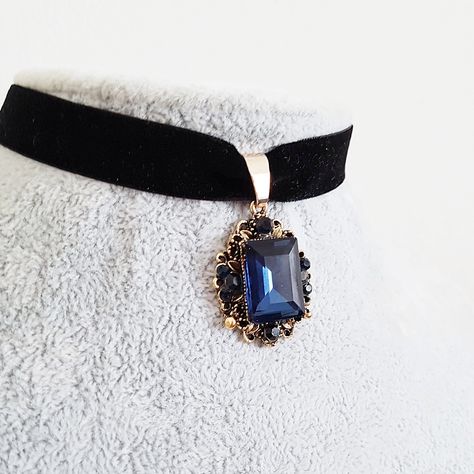 A Victorian style vintage gold plated glittering ornate dark sapphire blue crystal jewel drop is suspended from a black velvet choker. Choose your length in inches from the drop down menu.  The ornate drop measures 1 1/4 inches (30 mm) from top to bottom, and glitters with a rich blue main rectangular crystal surrounded by smaller ones. The velvet ribbon has a lobster clasp and 2 inch (50 mm) extension chain. To choose your length, measure the length of a choker that fits your neck comfortably a Princess Choker, Dark Blue Jewelry, Victorian Accessories, Blue Choker, Black Velvet Choker, Dark Sapphire, Magical Jewelry, Velvet Choker, Jewel Box