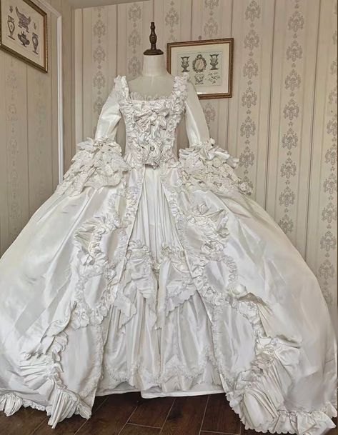 This stunning Luxury Antique Baroque Style Satin Wedding Dress with Floral Long Sleeves is the perfect choice for the bride who wants to make a statement on her special day. This 1800 ball gown features a beautiful baroque-inspired design with intricate details and luxurious satin fabric. The bodice is fitted with a sweetheart neckline, and the long sleeves are adorned with delicate floral appliques. The skirt is full and voluminous, with a sweeping train that adds a dramatic touch. This dress i 1700 Wedding Dress, Wedding Dress Antique, Old Princess Dresses Ball Gowns, Georgian Wedding Dress, Victorian Era Wedding Dress, Ball Gown Wedding Dress With Sleeves, 1700s Wedding Dress, Huge Ball Gowns, Versailles Costumes