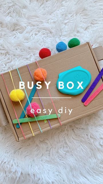 Wendy | Pediatrician on Instagram: "Hope you find this as satisfying as she did 😆🥰 Have you tried making a busy box before? It’s SUPER easy and such an entertaining way for littles to explore and work on fine motor skills 🧠 Best part? Everything I used was something recycled or a common craft item we already had 🙌🏻 SAVE this for inspiration! ⭐️ SUPPLIES / TOOLS ⭐️ ✔️ Cardboard box ✔️ Toilet paper roll ✔️ Rubber bands ✔️ Pom poms ✔️ Popsicle sticks ✔️ Markers ✔️ Wipes lid ✔️ Velcro dots Diy Object Permanence, Sensory Cardboard Box Ideas, Wipes Lid Crafts, Diy Toys For Infants, Cardboard Montessori, Wipe Lid Crafts, Velcro Activities For Toddlers, Diy Baby Toys 9-12 Months, Diy Infant Toys