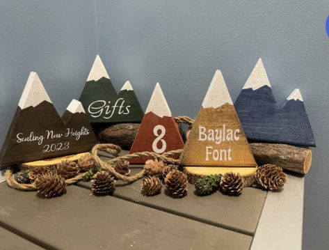 Decorative wooden mountains are perfect for wedding centerpieces, bridal shower decorations, nurseries or rustic decor.   Mountain peaks can be easily customized by adding lettering or numbering.  Mountains can be purchased as single, twin, triple or quad  peaked and can feature white snow caps if desired.  Standard mountain dimensions are approximately 6" x 6" . High quality permanent vinyl personalization (custom) available! We do special requests! Wood Mountain Centerpiece, Mountain Centerpieces, Table Number Photos, Mountain Table Numbers, Wooden Mountains, Family Reunion Keepsakes, Hiking Wedding, Table Numbers Wedding Rustic, Rustic Table Numbers