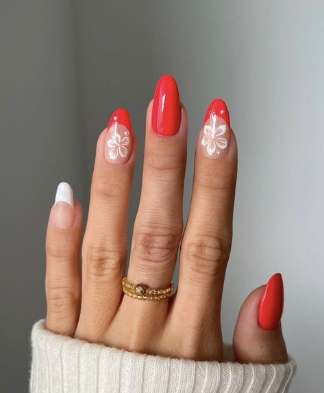 A girl with red French tip nails and two little white flower designs. Red Flower French Tip Nails, Red Nails Acrylic Summer, Nails Summer Oval, Red Hawaiian Nails, Hawaiian Vacation Nails, Red Tropical Nails, Oval Summer Nails, Summer Nails Oval, Summer Oval Nails