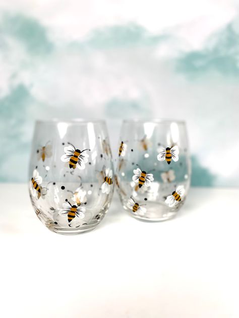 These are a pair of hand painted honey bee art stemless wine glasses.  What a great gift for Mom or any special occasion for celebrating friends and family.   This design is becoming very popular with customers.  * The glasses stand 5 inches tall and hold 18 fluid ounces    * This glass which can be used for many different purposes as well.  For example a small vase, on a desk to hold pens, or in the bathroom with a small candle.   * The  bee design is painted  around the glass many times with added black and white polka dots..  It is very charming and great for bee lovers for sure.   * Please remember to hand wash as well. * Functional Art, Custom orders are available on all orders when available. * Handpainted cards available except during December. * Gift wrap and card upon request avai Painting Drinking Glasses Diy, Hand Painted Glass Jars, Hand Painted Glass Cups, Paint Glasses Wine Diy, Painted Glassware Ideas, Drinking Glass Painting, Easy Painted Wine Glasses, Stemless Wine Glass Painting Ideas, Art On Glass Paint