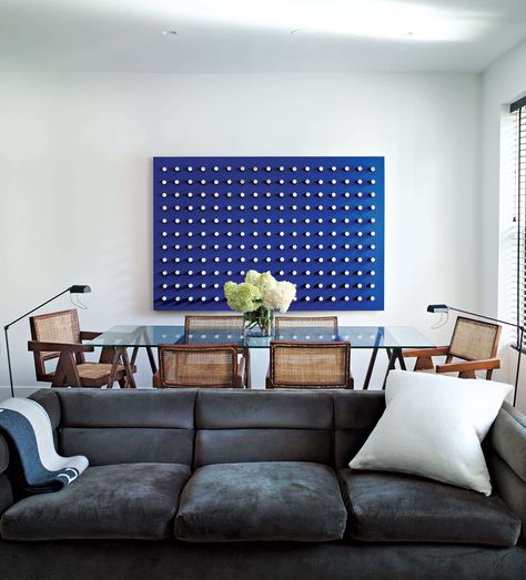 A set of six Pierre Jeanneret chairs surrounds a glass tabletop that rests on a pair of vintage sawhorses.  The sofa is by Edward Wormley. The throw is by Hermès.  Photo: Annie Schlechter Pierre Jeanneret Chair, Rental Makeover, West Village Apartment, Interior Design Secrets, Edward Wormley, Iconic Chairs, Minimalist Apartment, Nyc Design, Contemporary Dining Room