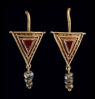 Pair of Roman gold, garnet, and glass earrings, c. 2nd-3rd century A.D. Each with a hooked earwire beaded along its length and tapering to a point, joined to a sheet triangle with a beaded wire fringe, a triangular garnet bezel-set in the center and framed by beaded wire and granulation, a loop at the base joined to a length of wire threaded with three blue glass beads. Each: 1 5/8 in. (4.1 cm.) long. (Photo: Christie's Images Ltd. 2010.) Imperiul Roman, Ancient Roman Jewelry, Ancient Jewels, Roman Jewelry, Ancient Jewellery, Historical Jewellery, Medieval Jewelry, Ancient Jewelry, Old Jewelry