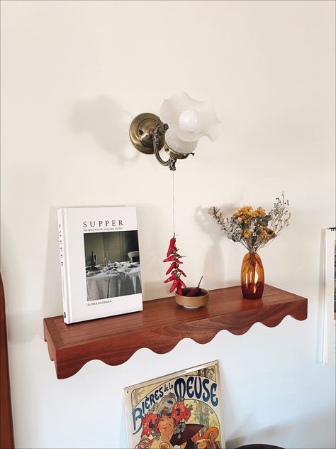 Wavy bookshelf with a recipe book, hanging chillis and flowers in a small vase Wavy Bookshelf, Above Tv Shelf, Wavy Shelves, Chilli Art, Shelf Above Tv, Apartment Diys, Wavy Shelf, Art Above Tv, Lovers Bedroom