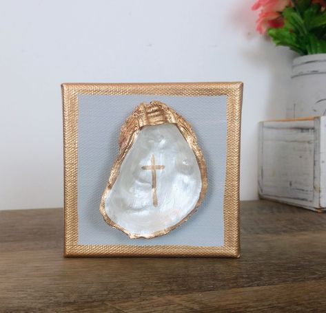 Small Real Oyster Shell on a 4x4 gallery (thick) canvas. Oyster is painted in pearl white, adorned with a simple gold cross, and rimmed in liquid gold leaf. Canvas background is a simple gray, allowing the shell to be the focal point. Perfect little piece to display on a desk or shelf, or on your entryway table. Additional canvas colors available upon request. Just message me and I'll work with you to come up with the perfect piece for your space. Oyster Shell On Canvas, Oyster Shell Art Paintings, Oyster Shell Cross Diy, Oyster Wall Art, Crafts With Oyster Shells, Diy Small Canvas Art, Oyster Shell Painting, Oyster Shell Crafts Diy How To Make, Painted Oyster Shells Ideas