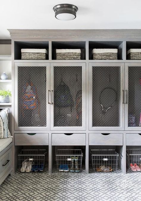 White and gray geometric floor tiles sit beneath vintage metal bins positioned under gray wash wooden drawers and gray wash closed lockers finished with metal lattice door fronts. Garage Lockers, Mudroom Cubbies, Metal Bins, Metal Lattice, Mud Room Entry, Mudroom Lockers, Mudroom Laundry Room, Geometric Floor, Mud Room Storage