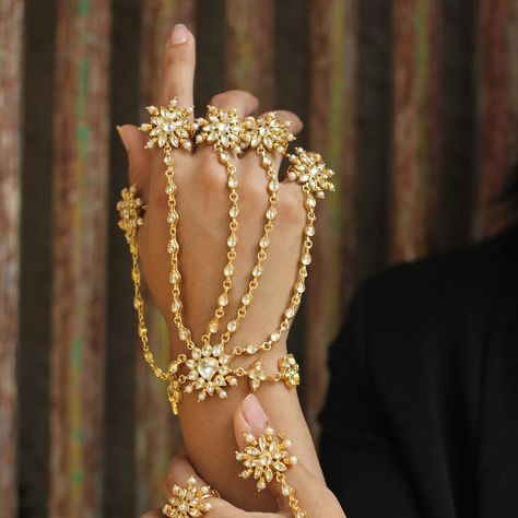 This exquisite set of gold hand harnesses, known as ‘Hathphool’ in traditional jewelry, embodies the essence of intricate craftsmanship and opulence. Each harness features a mesmerizing array of delicate floral motifs, meticulously designed with radiant pearls and glimmering gemstones, cascading gracefully from the rings to the wrists. The gold chains, intricately linked, create a harmonious blend of traditional artistry and contemporary elegance.✨🌸 Prefer a closer look? Book a video call fo... Hand Harness, Bedroom Decor Cozy, Gold Hand, Hand Chain, Video Call, Gold Hands, Look Book, Traditional Jewelry, Floral Motifs