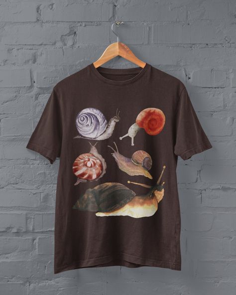 Thanks for stopping by! Cottagecore Snails T-shirt Printed on a super soft, cotton tee Dispatched in 5 working days or sooner Unisex Free UK delivery Material: 100% ringspun cotton. Chest (to fit): S  34/36   M  38   L  40/42   XL  44/46   XXL  48/50 ECO-FRIENDLY Each garment is made to order, reducing extra material and energy that would be otherwise wasted We use DTG printing process which is easier on the environment than screen-printing Our ink is bright and also eco-friendly. Do not tumble Different Aesthetic Clothes, Goblincore Goth, Art On T Shirt, Bug Clothes, Goblincore Shirt, Goblincore Fashion, Fairycore Clothing, Bug Shirt, Art Tshirt