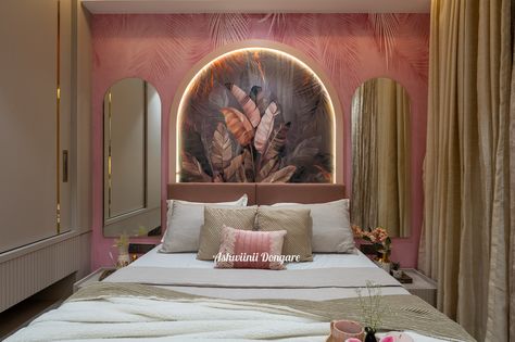 The overall color scheme incorporates warm tones of blush pink, soft beige, and muted brown. The pink accent wall behind the bed adds vibrancy while the neutral tones balance the space, creating a calm and the welcoming atmosphere. The headboard is simple, upholstered in a soft pink fabric. Above it, the focal point is the arch-shaped back panel with a tropical-themed mural. The leaves in various shades complement the natural tones in the room. The LED backlighting behind the arch highlights... Arch Behind Bed, Pink Accent Wall, Small Bedside Tables, Arched Mirrors, Pink Accent Walls, Neutral Curtains, Muted Brown, Small Bedside Table, Bed Back