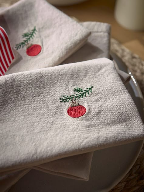 Crafted from cotton, our embroidered bauble napkins are the perfect combination of Christmas décor with a subdued and minimalist feeling.        With a simple embroidered bauble on the right hand side, the neutral background complements the minimal design creating a napkin that will blend into any dining setting seamlessly.       A matching table runner is also available.        Explore the rest of our Regency Romance collection. Embroidery Christmas Napkins, Embroidered Napkins Christmas, Christmas Embroidery Napkins, Christmas Napkins Embroidery, Embroidered Christmas Napkins, Napkin Embroidery, Embroidery Napkins, Notes Craft, Christmas Table Linen