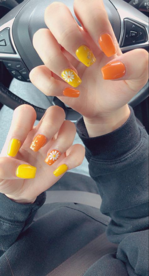 opposite designs and colors on each hand. cute flower and some gold foil used on acrylics. Yellow Nail Paint, Yellow Orange Nails Acrylic, Yellow And Orange Nails Summer, Orange Yellow Nails Summer, Yellow Orange Nails Design, Pretty Orange Nails, Yellow And Orange Nails Design, Nails Summer Yellow, Orange And Yellow Nail Designs