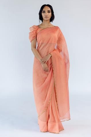 Peach hand crushed saree with scallop embroidered hem. Comes with an unstitched blouse piece. Component: 2 Pattern: Embroidered Fabric: Tissue Silk Color: Peach Other Details:  Hand crushed texture Note: Blouse worn by the model is not for sale Occasion: Puja - Aza Fashions Crushed Saree, Peach Color Saree, Saree Women, Banaras Sarees, Embroidered Hem, Tissue Saree, Saree For Women, Elegant Blouse Designs, Embroidered Fabric