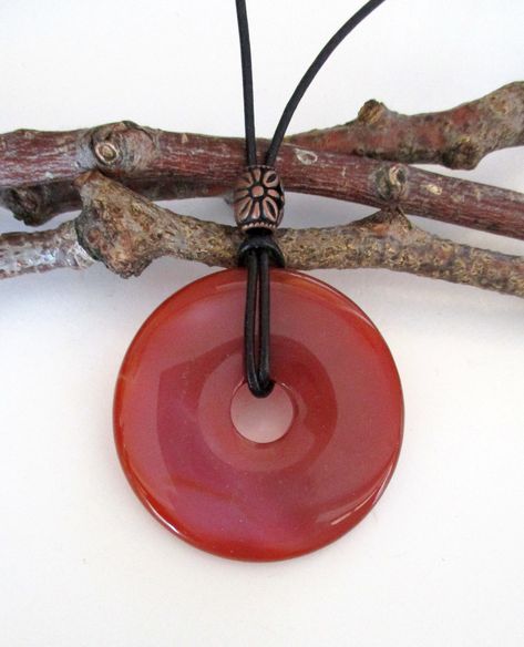 "Red Agate Natural Semi Precious Gemstone Donut Energy Pendant Necklace.  50mm.  ED474 /  ED474-4 / ED474-6 / ED474-7 Measures approx. 50 x 7mm = 2\" x ¼\".  Suspended on a continuous 31\" leather cord strand without a clasp closure and accented with a bronze tone Tibetan style bead.  Choose black or natural color leather cord. Makes a unique gift for any occasion.  The one you choose is the one you will receive.  From a smoke and pet free environment.   You can always check the internet for the meaning, physical and healing properties and uses of the different colors of AGATE. Please make sure that you look at all the photos in order to help you with the measurements and details. Any questions or concerns, please feel free to contact us. SHIPPING:   Items will be shipped by USPS the next Different Shades Of Red, Cool Piercings, Red Agate, Agate Pendant, Healing Properties, Shades Of Red, Semi Precious Gemstones, Leather Cord, Amazing Jewelry