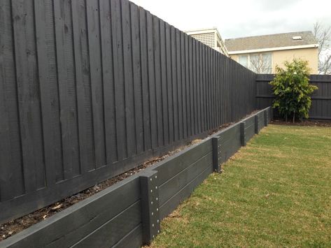 Black Wood Retaining Wall, Painted Timber Retaining Wall, Retaining Wall Side Of House, Modern Farmhouse Retaining Wall, Concrete Retaining Wall Makeover, Retaining Wall Under Fence, Black Retaining Wall Garden, Black Retaining Wall, Fence Retaining Wall