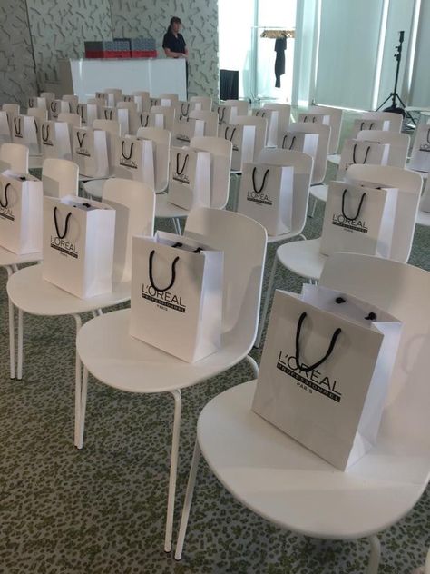 Simple and Minimalistic corporate event chair arrangement with souvenir bags Fashion Show Gift Bags Ideas, Event Goodie Bags, Beauty Masterclass Event, Makeup Launch Event, Work Event Decor, Makeup Event Ideas, Beauty Event Decor, Conference Decorations Events Ideas, Makeup Goodie Bags Ideas