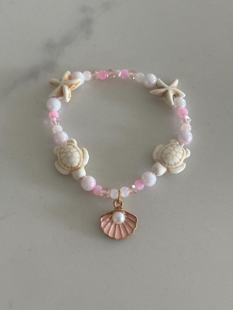 Pink Beach themed bracelet with turtle and starfish beads plus a shell charm with a pearl. Includes an assortment of beautiful light pink beads that looks like a sunset Mermaid Pearl Jewelry, Bracelet Beach Summer, Beach Theme Bracelets, Shell Bracelet Aesthetic, Beaded Bracelets Beach, Sea Shell Bracelet Diy, Clay Bead Bracelet Pink, Beachy Clay Bead Bracelet, Beach Bracelet Ideas