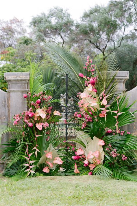 Hawaiian luxury wedding backdrop of tropical foliage and pink florals #WeddingChicks #HawaiianWedding #pinkceremonybackdrop #pinkceremonyarch #tropicalwedding #tropicalweddingbackdrop Tropical Arches Wedding, Tropical Backdrop Wedding, Tropical Wedding Alter, Tropical Flower Backdrop, Tropical Floral Installation, Tropical Chuppah, Tropical Wedding Backdrop, Tropical Greenery Wall, Birds Of Paradise Wedding