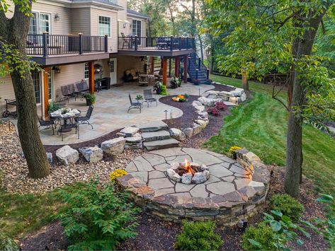 Adding a Patio Under Your Deck: Tips and Ideas for Homeowners in Lancaster and Reading, PA Fire Pit Ideas Backyard Flagstone, Fire Pit Wall Ideas, Fire Pit With Seating Wall, Boulder Fire Pit Ideas, Flagstone Patio Design Ideas, Flagstone Patio Ideas On A Budget, Boulder Patio, Pebble Fire Pit Area, Lake House Landscaping Ideas