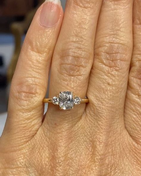 Cynthia Britt Custom Jewelry on Instagram: "A beautiful engagement ring for lovely Brenda! 🌟Story: Kathryn wanted a surprise engagement ring for Brenda. She had asked Brenda about her preferences so when time came, she asked her friends Scott and Kate, (I have created their engagement ring, wedding bands and a baby gift) for a recommendation and they referred me.  Kathryn knew Brenda liked an elongated cushion cut diamond preferably in a three stone ring. She was open to suggestions for both the center diamond and the style of the ring.  I first brought her a few diamonds to pick from and she chose an amazingly cut cushion brilliant cut diamond. Based on her chosen diamond and Brenda's hand structure and personal style, I recommended one round brilliant cut diamond on either side of the Three Square Diamond Ring, 3 Stone Elongated Cushion Engagement Ring, Elongated Cushion Three Stone Engagement Ring, Unique Three Stone Engagement Rings, Elongated Cushion With Side Stones, Cushion Cut Three Stone Engagement Ring, Three Stone Cushion Engagement Rings, Elongated Cushion Three Stone, Three Diamond Engagement Rings