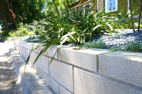 A DIY Cinder Block Retaining Wall Project Breeze Block Retaining Wall Garden, Concrete Block Retaining Wall Ideas, Block Retaining Wall Ideas, Cinder Block Retaining Wall, Cinder Block Garden Wall, Cheap Retaining Wall, Concrete Block Retaining Wall, Block Retaining Wall, Retaining Wall Ideas