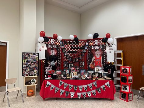 School colors: Red, Black, & White. We built a background with Lattice and painted it Red. I purchased the “Soccer” , “Basketball” , and “Baseball” signs from Hobby Lobby, then painted them black. I purchased the 5x7 picture frames from dollar tree. I used floral wire and attached them all together. They are 5x7s from 5K to 12th grade. I purchased the numbers from hobby lobby and painted them white. I purchased the grad boxes from Amazon. I purchased the black chalkboard buckets from Hobby Lobby Rustic Senior Table, Senior Display Table Ideas For Sports, Soccer Signing Day Table, Senior Night Table Display Cheer, Graduation Sports Display, Senior Sports Boards, Cap And Gown Display For Party, Jerry Graduation, Senior Baseball Table Ideas