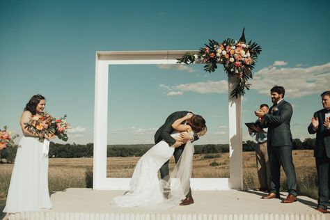 Jordyn and Kyle shared their first kiss under a sleek, contemporary white wedding arch adorned with an orange and pink corner floral arrangement. Wedding Arch Alternative, Wedding Venues Scotland, White Wedding Arch, Church Wedding Flowers, Wedding Ceremony Arch, Unique Wedding Flowers, Wedding Ceremony Backdrop, Frame Wedding, Wedding Picture Frames