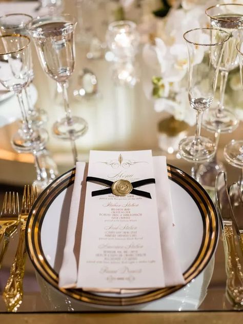 wedding menu card decorated with black ribbon and gold wax seal on top of gold-rimmed dinner plate Gold Place Setting, New Year's Eve Wedding, New Years Wedding, Nye Wedding, New Years Eve Weddings, Black White And Gold, Wedding Menu Cards, Event Company, Glamorous Wedding