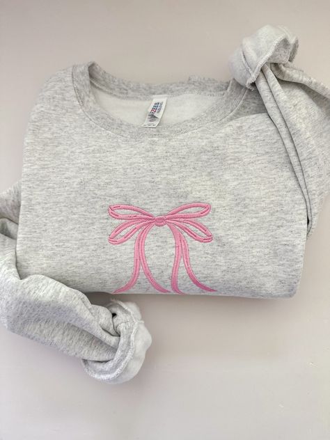 Stay chic in this minimal embroidered bow crewneck! Embroidered on a cotton blend sweatshirt, this minimal, dainty design is sure to go with any cute outfit! Embroidery Items To Sell, Boutique Sweatshirts, Bow Sweatshirt, Embroidered Bow, Ribbon Gift, Bow Ribbon, Cute Preppy Outfits, Cute Sweatshirts, Cute Everyday Outfits