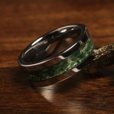 "Elevate your special moments with our stunning Green Moss Agate Tungsten Ring. This unique piece is not just a symbol of commitment but a statement of individuality and style. Crafted with high-quality black tungsten, this ring features a mesmerizing green moss agate inlay that showcases the beauty of nature. As a unisex ring, it offers versatility for both men and women seeking an extraordinary wedding band, anniversary token, or an engagement or promise ring. The black tungsten band provides Stone Rings Mens, Tree Ring Men, Cheap Green Rings For Gifts, Mens Wedding Ring Cool, Male Promise Rings Stone, Earthy Wedding Rings For Men, Men’s Wedding Rings For Rugged, Mens Wedding Rings Gay Friendly, Nut Mens Wedding Rings