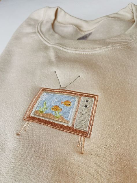 Embroidered Aquarium TV Sweatshirt

Cozy up in this embroidered sweatshirt featuring a colorful aquarium TV. Perfect for lounging around the house or running errands. Find it on now! #embroidery #sweatshirt #aquarium . #Upcycling #Machine_Embroidery_Designs_Sweatshirt #Simple_Shirt_Embroidery #Fall_Sweatshirt_Ideas Embroidery Inspiration Clothing Sweatshirts & Hoodies, Cotton Crew Neck Sweatshirt With Embroidered Patch, Embroidered Clothes Ideas, Hoodie Embroidery Ideas, Sweatshirt Embroidery Ideas, Chilly Fits, Sweatshirts Ideas, Hoodie Art, Embroidery Business